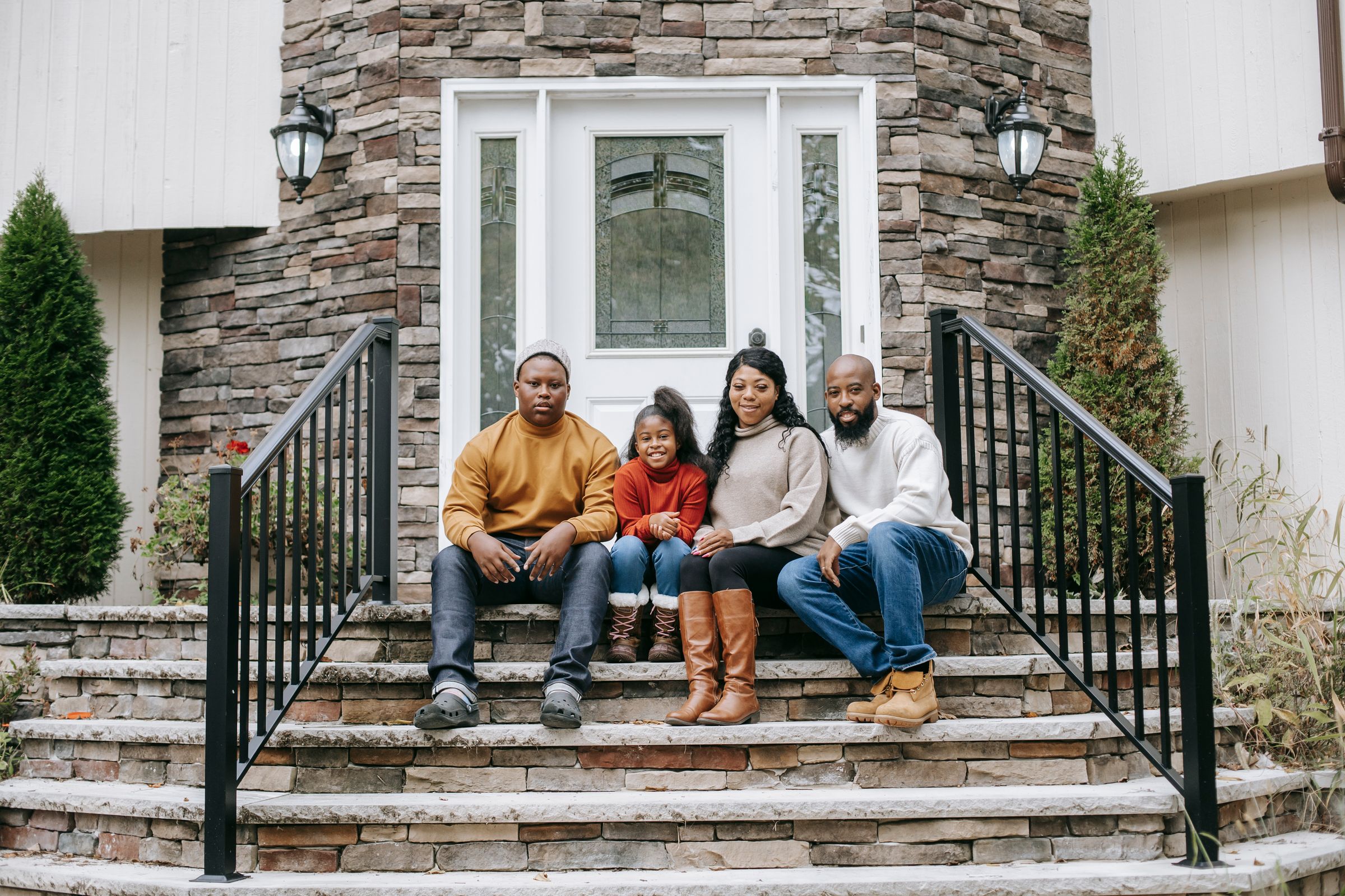 A family sitting together on the front steps of their home